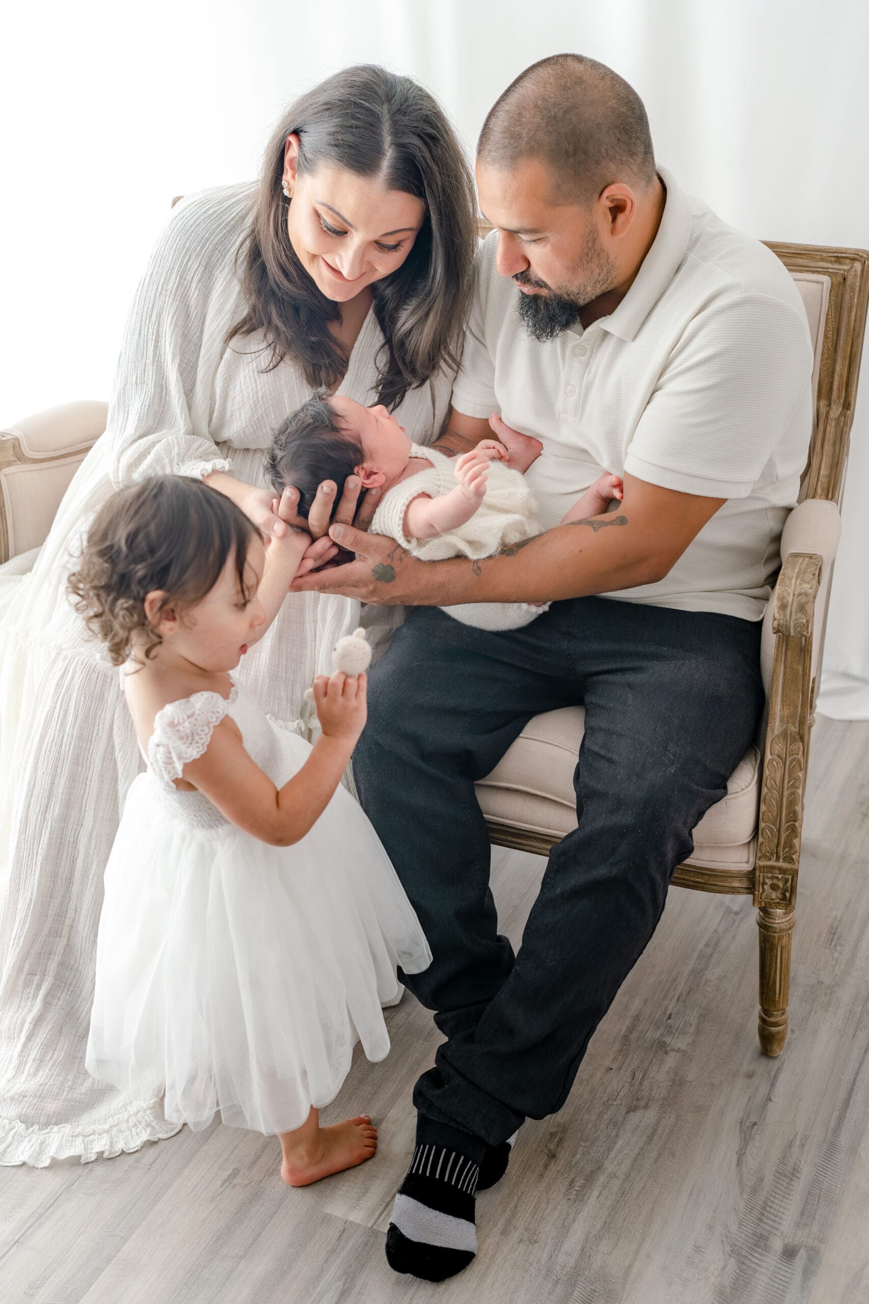Alliston newborn photographer captures parents and siblings in bright studio setting

